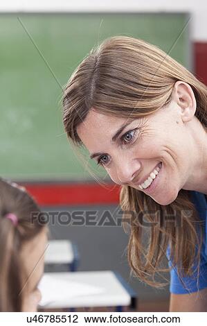 Stock Image - Teacher looking at pupil and smiling. Fotosearch