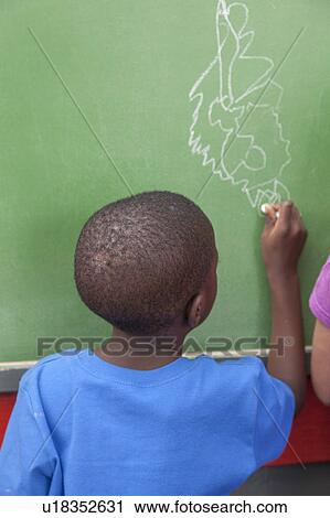 Stock Image - The boy drawing at the blackboard. Fotosearch