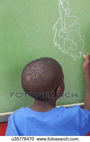 Stock Image - The boy drawing at the blackboard. Fotosearch