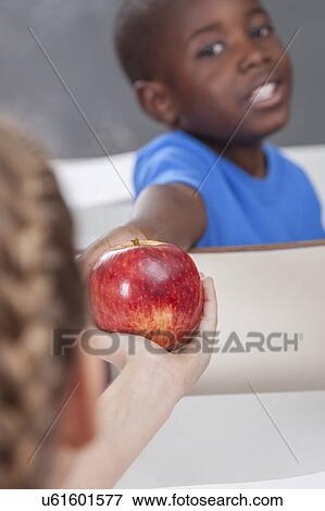 Stock Photo - The boy giving an apple. Fotosearch