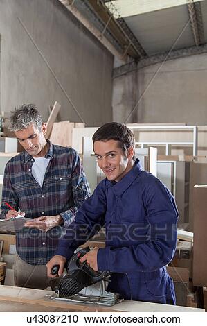 Stock Image - The carpenter with his assistant. Fotosearch
