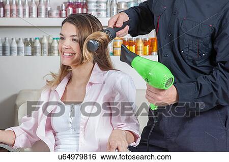 Stock Photograph - The coiffeur drys the hair one woman. Fotosearch