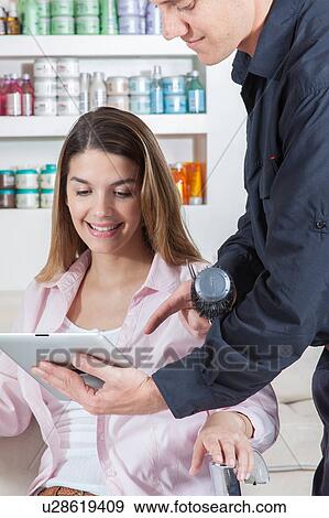 The coiffeur showing to one woman the ipad View Large Photo Image Stock Photo - The coiffeur showing to one woman the ipad. Fotosearch