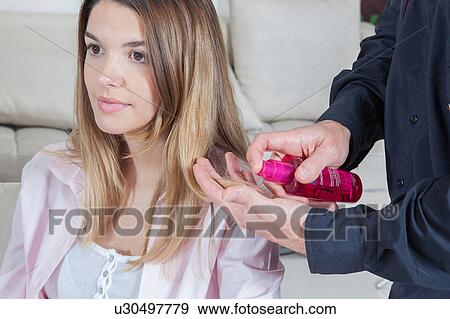 Stock Photo - The hairdresser applies a lotion in the hair of a woman. Fotosearch