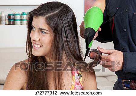 Stock Image - The hairdresser drys the hair one happy woman . Fotosearch