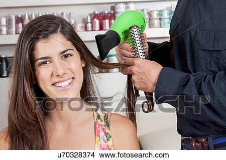 Picture - The hairdresser drys the hair one woman . Fotosearch