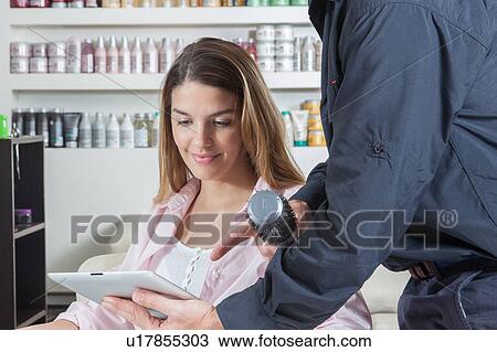 Stock Image - The hairdresser showing to one woman the ipad. Fotosearch