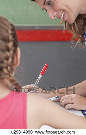 Stock Image - The teacher checking the homework. Fotosearch