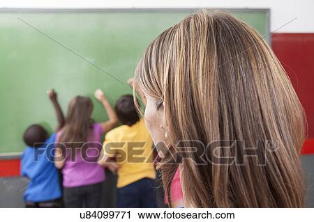 Stock Image - The teacher looking at hers students. Fotosearch