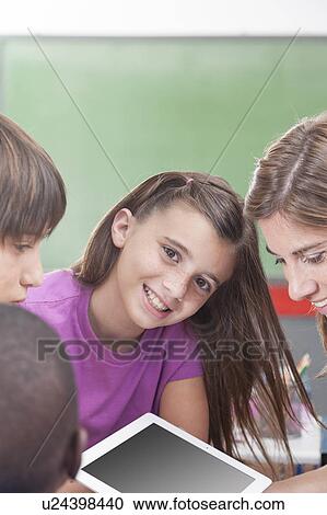 Stock Image - The teacher showing something and girl looking at camera. Fotosearch