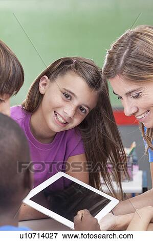 Stock Photo - The teacher showing something and girl looking at camera. Fotosearch