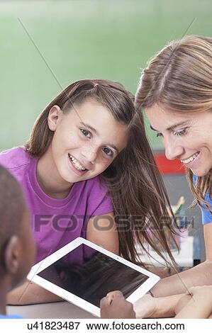 Stock Photo - The teacher showing something and girl looking at camera. Fotosearch
