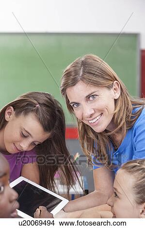 Picture - the teacher showing something and looking at camera. Fotosearch