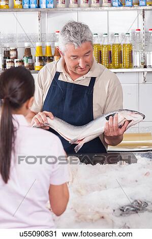 Stock Image - Woman buying a pink salmon. Fotosearch