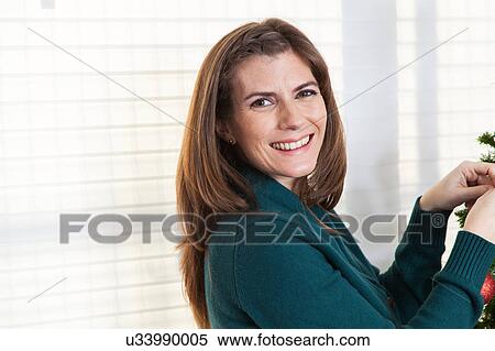 Stock Photography - Woman decorating christmas tree. Fotosearch