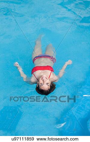 Woman floating in the pool View Large Photo Image Stock Photo - Woman floating in the pool. Fotosearch