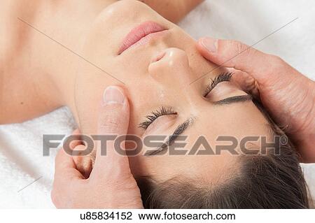 Stock Image - Woman gets a massage on her face. Fotosearch