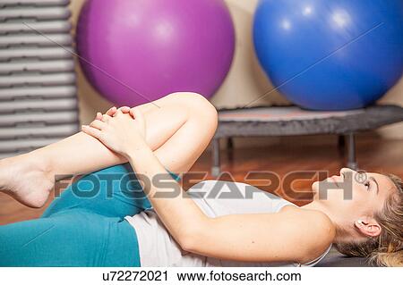 Stock Image - Woman lying doing yoga. Fotosearch
