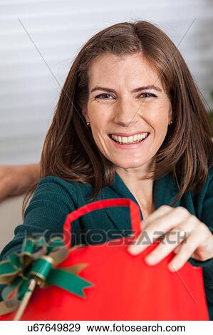 Stock Photo - Woman opening the gift and smiling. Fotosearch