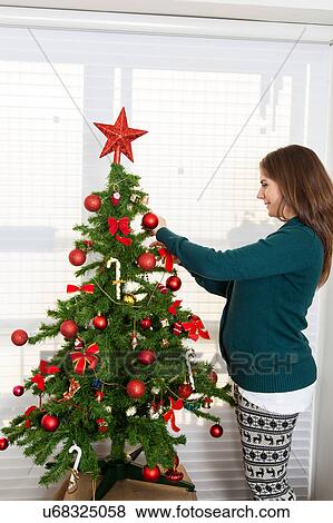 Woman pregnant decorating a christmas tree View Large Photo Image Stock Photo - Woman pregnant decorating a christmas tree. Fotosearch