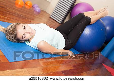 Stock Image - Woman stretching with a ball. Fotosearch