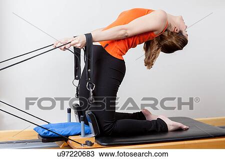Stock Image - Woman stretching with the machine. Fotosearch
