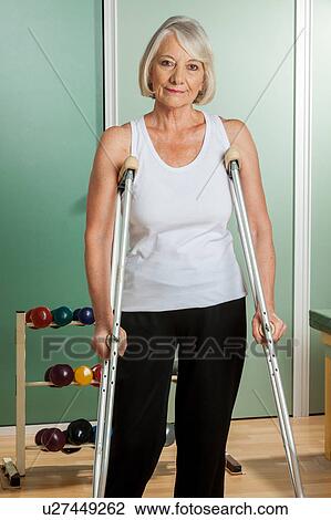 Stock Image - Woman with a neck brace using crutches. Fotosearch