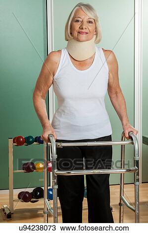 Stock Image - Woman with a orthopedic neck using the walker. Fotosearch