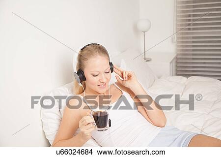 Picture - Young woman listening to music and drinking coffe. Fotosearch