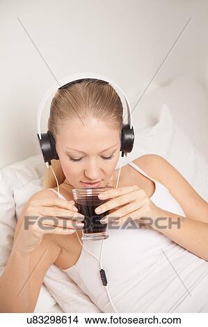 Picture - Young woman listening to music and drinking coffe. Fotosearch