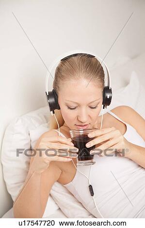 Stock Image - Young woman listening to music and drinking coffe. Fotosearch