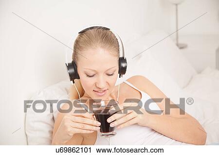 Young woman listening to music and drinking coffe View Large Photo Image Stock Image - Young woman listening to music and drinking coffe. Fotosearch