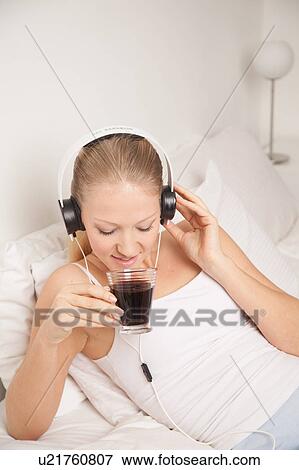 Stock Photo - Young woman listening to music and drinking coffe. Fotosearch