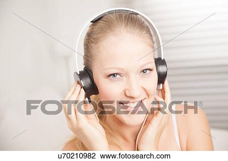Stock Image - Young woman listening to music. Fotosearch
