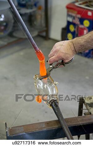 Glassblower cuts molten glass with a hand tool View Large Photo Image Stock Photograph - Glassblower cuts molten glass with a hand tool. Fotosearch
