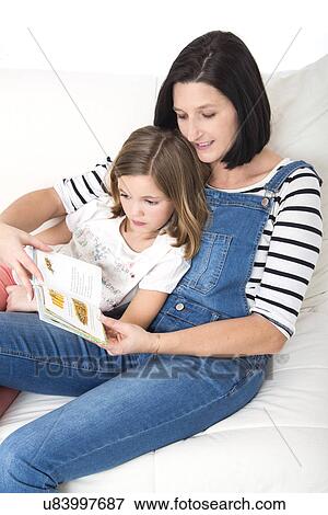 Stock Photo - Mother reading a book with her daughter.. Fotosearch
