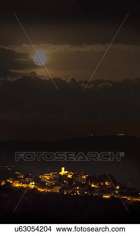 Picture - Umbrian medieval town of MonteCastello di Vibio, Italy with full moon rising in twilight.. Fotosearch
