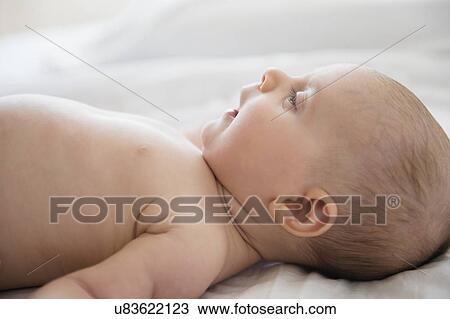 Stock Image - Baby girl (2-5 months) lying on bed. Fotosearch