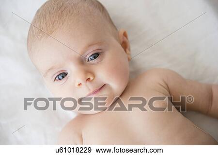 Stock Photo - Baby girl (2-5 months) lying on bed. Fotosearch