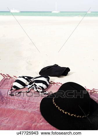 Stock Image - Bikini and sunhat on blanket on beach. Fotosearch