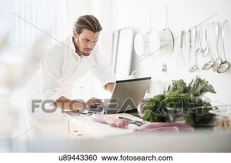 Chef using laptop in kitchen View Large Photo Image Stock Image - Chef using laptop in kitchen. Fotosearch
