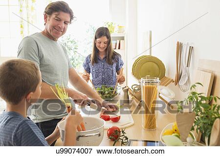 Children (8-9, 10-11) preparing food with their father View Large Photo Image Stock Photo - Children (8-9, 10-11) preparing food with their father. Fotosearch