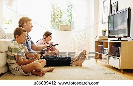 Stock Image - Children (8-9, 10-11) watching TV with their father. Fotosearch