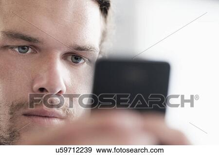 Stock Photo - Close-up of mid-adult man texting. Fotosearch