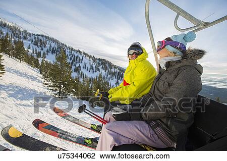 Couple in skiwear sitting on ski lift View Large Photo Image Stock Image - Couple in skiwear sitting on ski lift. Fotosearch
