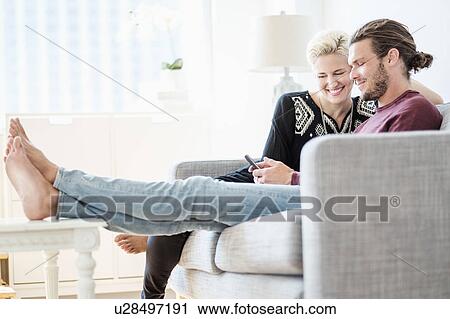 Couple laughing on sofa View Large Photo Image Stock Image - Couple laughing on sofa. Fotosearch