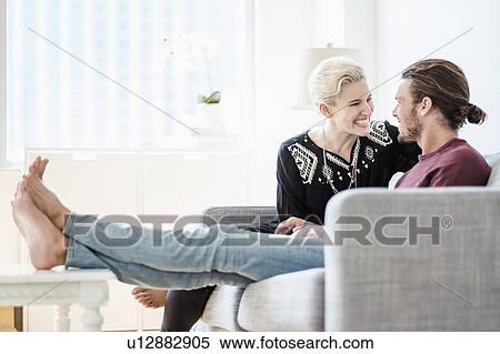 Stock Photography - Couple laughing on sofa. Fotosearch