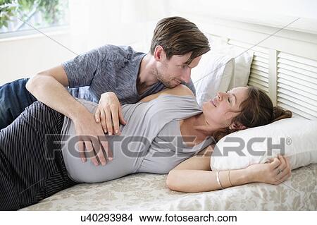 Couple lying in bed View Large Photo Image Picture - Couple lying in bed. Fotosearch