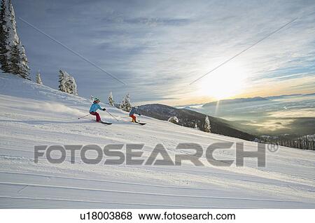Stock Photo - Couple skiing at sunset. Fotosearch