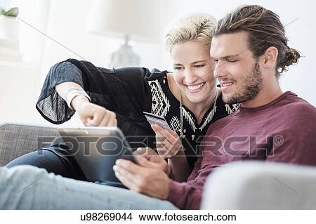 Picture - Couple using tablet pc on sofa. Fotosearch